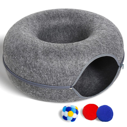 Gray donut-shaped pet bed with a small door and three colorful balls on a white background