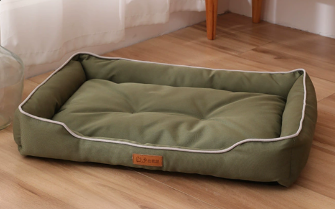 Green pet bed on a wooden floor with a white wall in the background